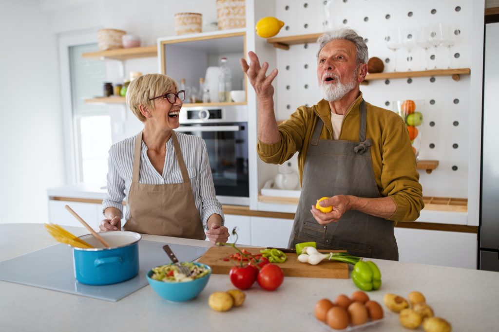 Senior couple having fun, cooking together in home kitchen