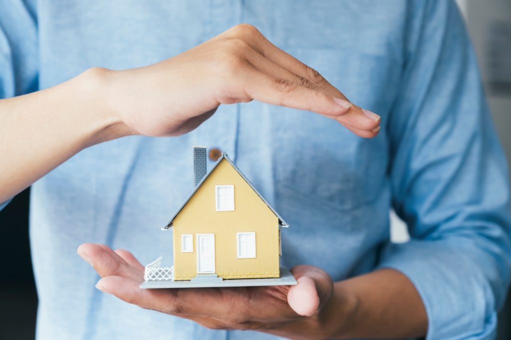 Business man hand hold the house model saving small house.
